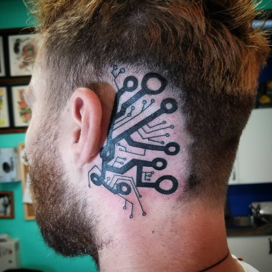 Circuit-like ear tattoo with black ink lines spreading from behind the ear
